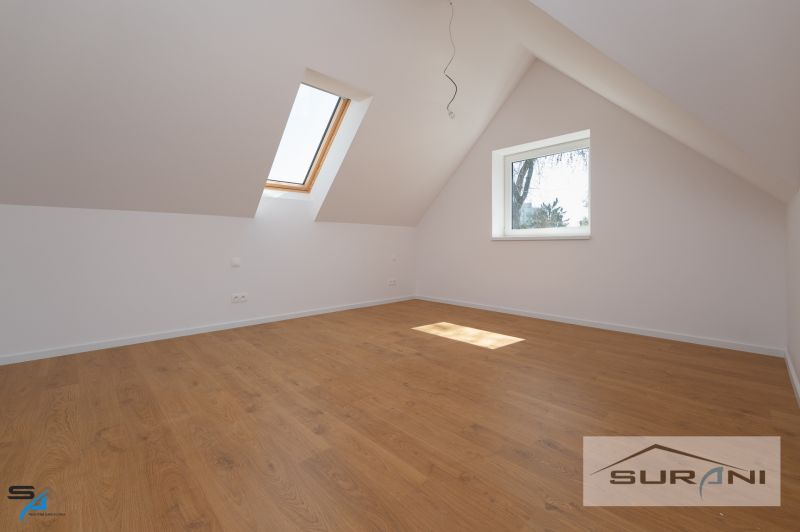 A room with windows and a wooden decor floor in a family house.
