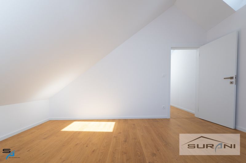 Attic room with white walls and a wooden decor floor in a family house.