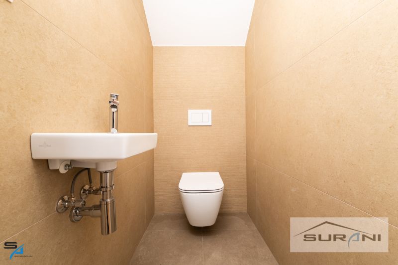A bathroom with beige walls in a family house with a toilet and a sink.