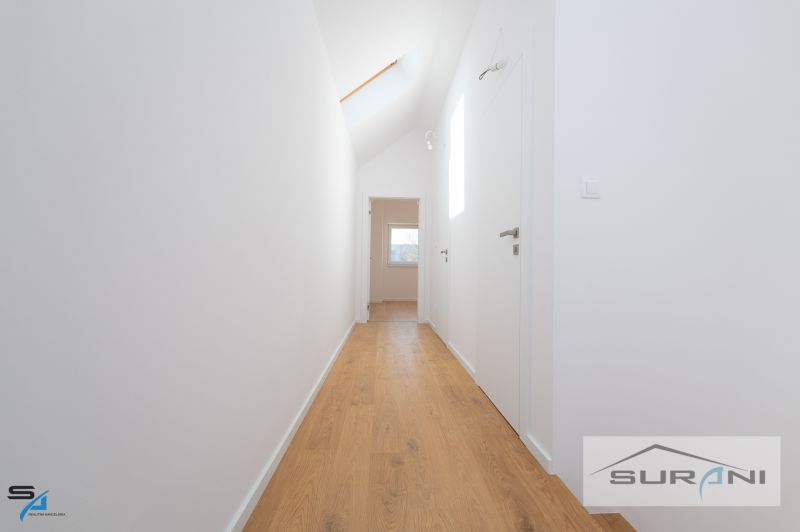 A hallway with a wooden decor floor in a family house, white walls and doors.