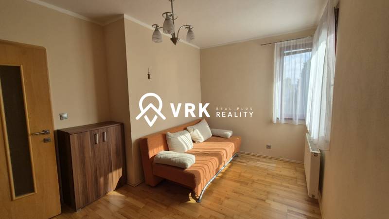 Living room with an orange sofa and wood-patterned flooring in a family house.