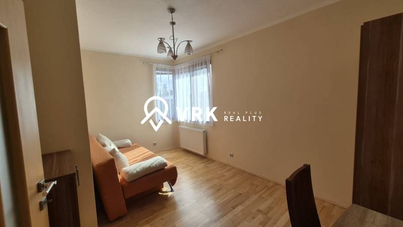 Living room in a family house with an orange sofa and a wooden decor floor.