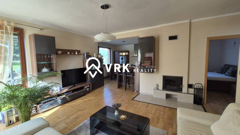 Living room in a family house with a wooden decor floor, fireplace, and comfortable seating.