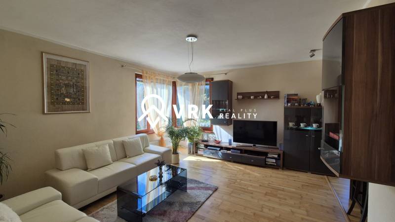 Living room in a family house with a sofa, TV, painting, and floor with wooden decor.