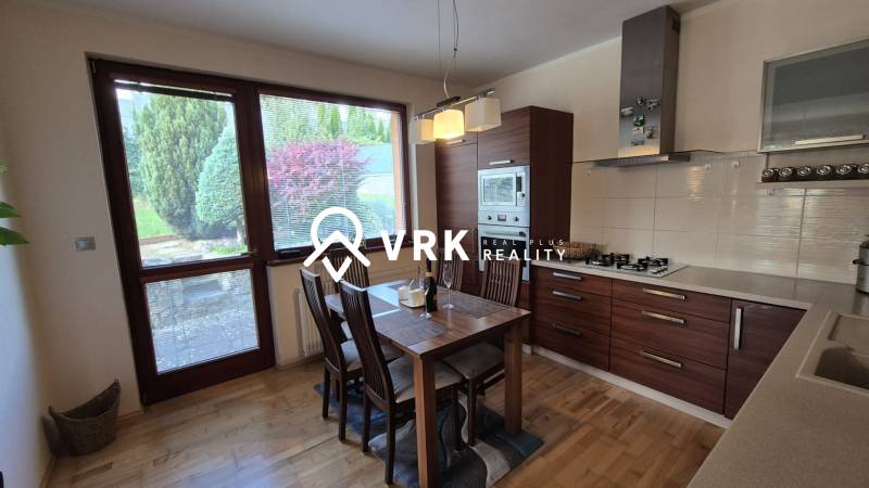 A kitchen in a family house with a wooden decor floor and a view of the garden.