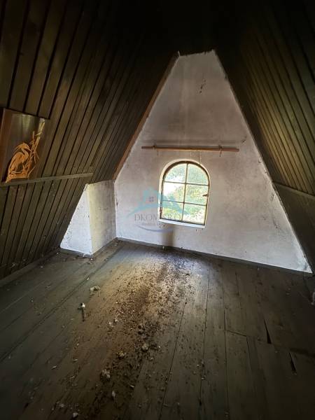 Attic room in a cottage with a window and a floor with wooden decor.