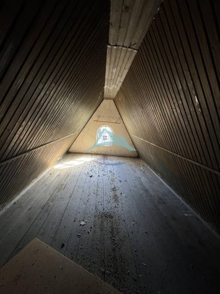 An attic room in a cabin with wooden walls and a wooden decor floor.