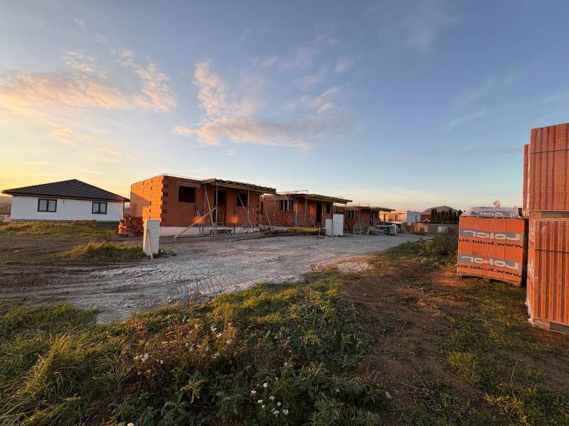 Construction of houses in Ľubotice during sunset, with visible brick walls.