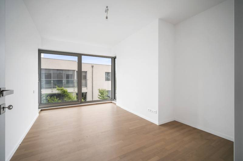 A bright room with a large window and a wooden decor floor in a 4-room apartment.