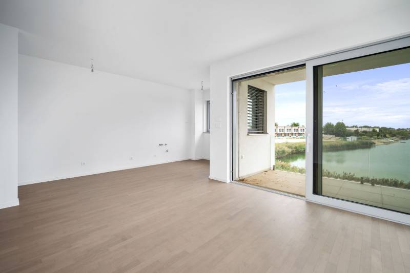 Interior of a 4-room apartment with a wooden decor floor and large glass doors to the terrace.