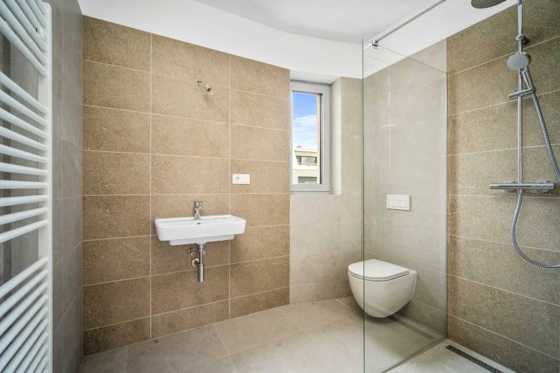 Bathroom with a shower, toilet, and sink in a 4-room apartment.