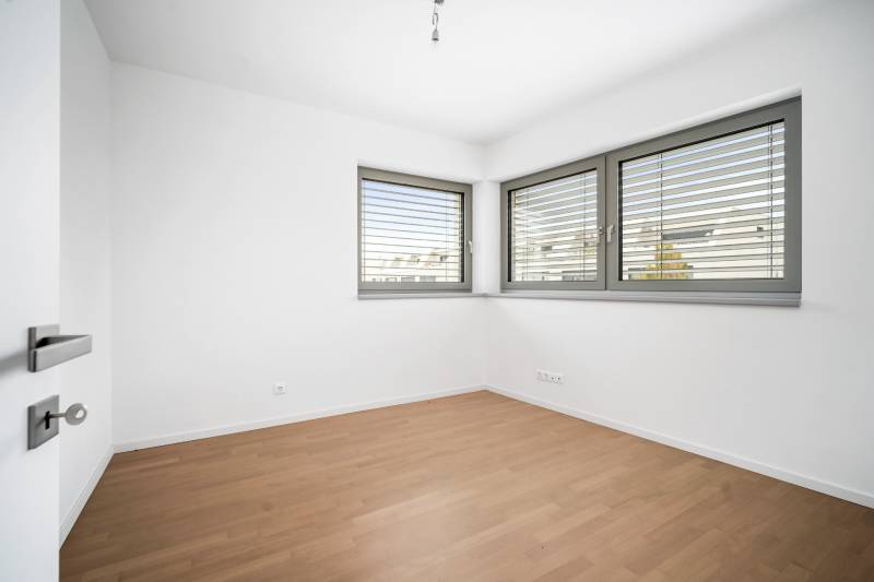 A room with a wooden decor floor and large windows in a 4-room apartment.
