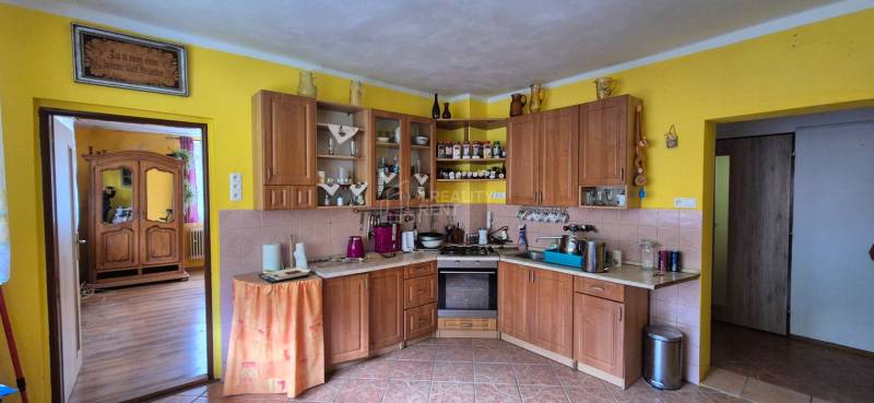 A kitchen in a family house with wooden decor on the furniture and yellow walls.