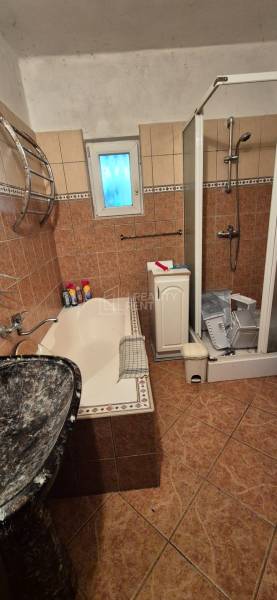 Bathroom in a family house with a bathtub, shower, and ceramic tiles.