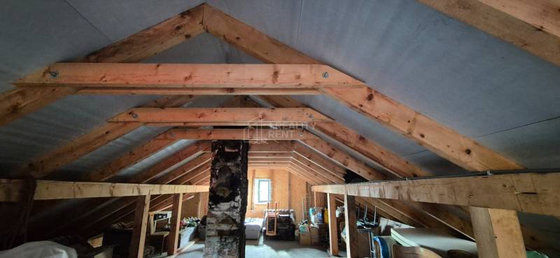 The attic of a family house with wooden beams and stored items.