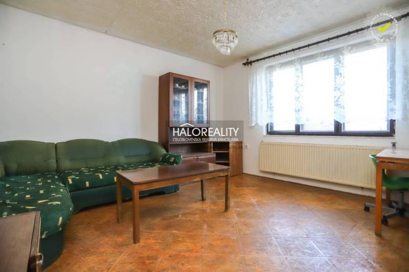 Living room in a family house with a corner sofa, coffee table, and glass display cabinet.