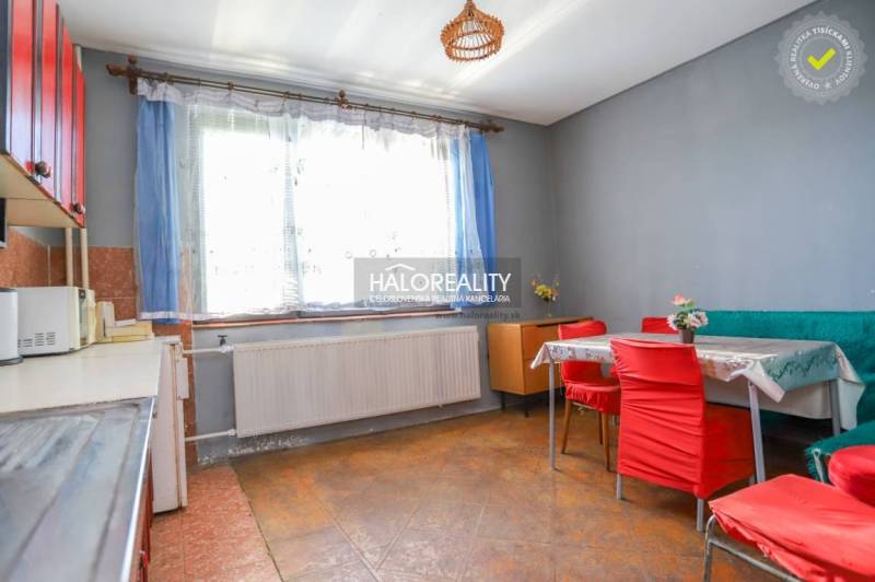 Kitchen with dining area in a family house, red chairs, gray walls, large window.