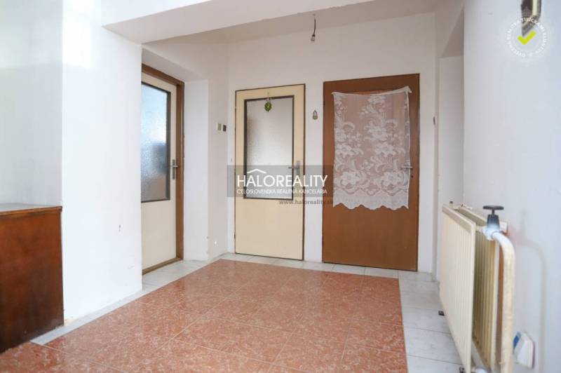 Entrance hall of a family house with tiles and two wooden doors.