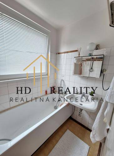 A bathroom with a classic bathtub, sink, and tiles in a 3-room apartment.
