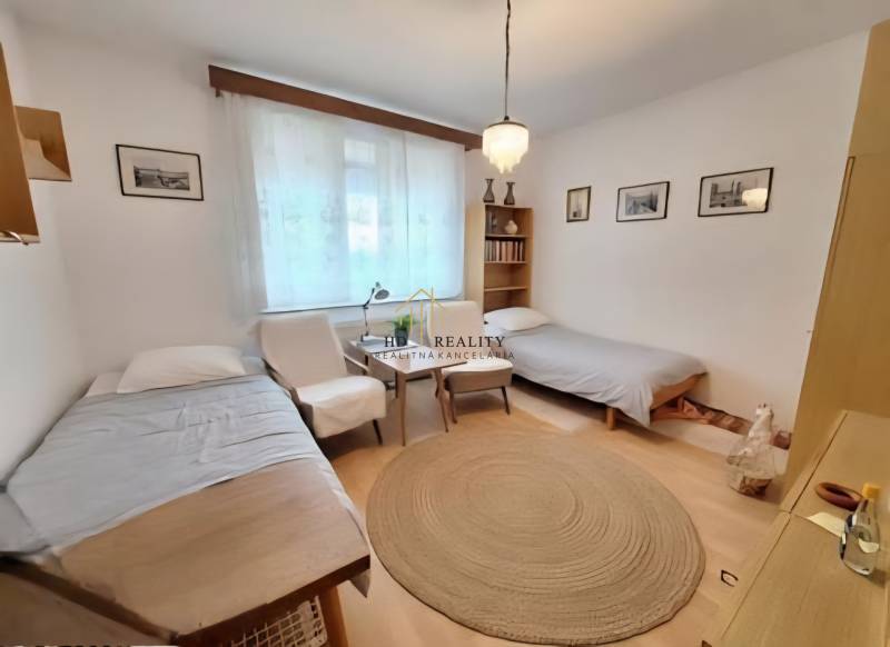 A bright room with curtains, two beds, an armchair, and a round carpet in a 3-room apartment.