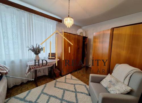 Living room in a three-room apartment with a light carpet and wooden decor on the furniture.