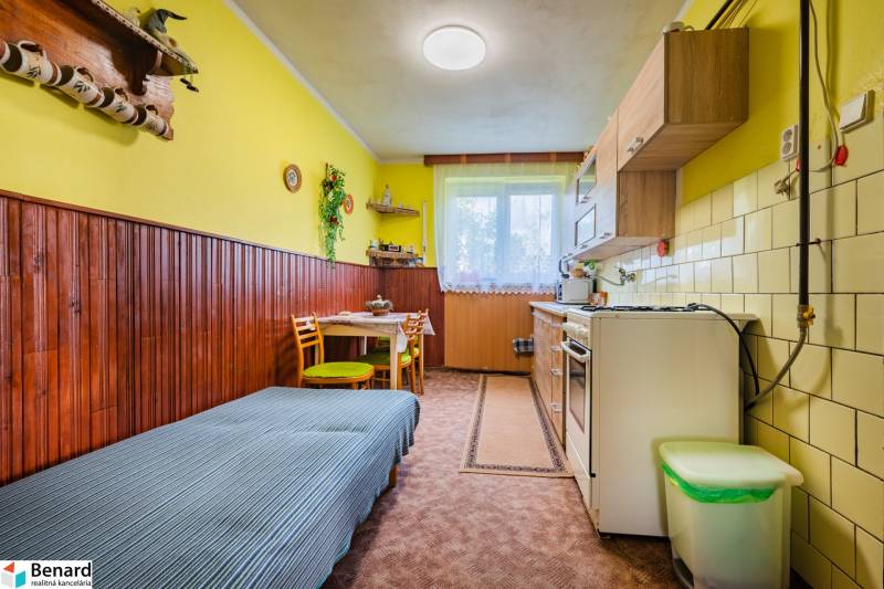 A kitchen with a dining table and a sofa in a 3-room apartment with yellow walls.