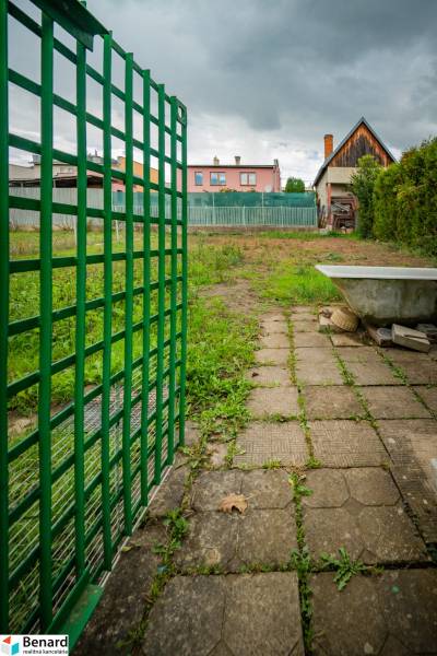 Garden on Matice Slovenská Street in Veľký Šariš with a fence and a paved walkway.