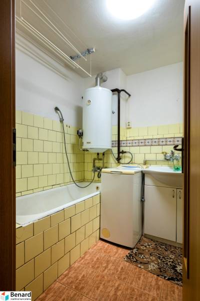 A bathroom in a 3-room apartment with a bathtub, washing machine, and gas boiler.