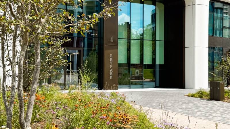 Entrance to the Sky Park building in Bratislava on Bottova, surrounded by trees and flowers.
