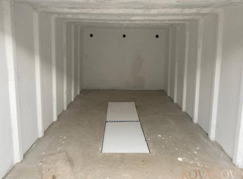 An empty garage with a rectangular opening on the floor, two walls in the Garage Trenčín on Legionárska.