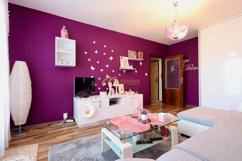 A colorful living room with white furniture, a glass table, and a wooden decor floor in a studio apartment.