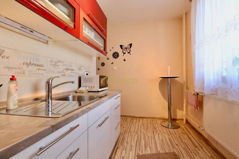 A kitchen in a studio apartment with red cabinets and a wood-patterned floor.