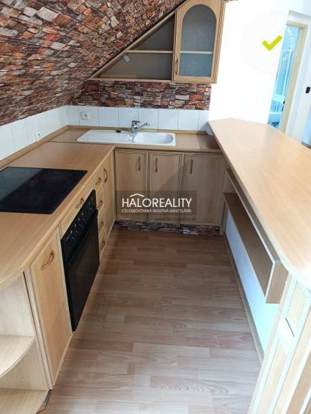 A kitchen in a 2-room apartment with a wooden decor floor and brick cladding.