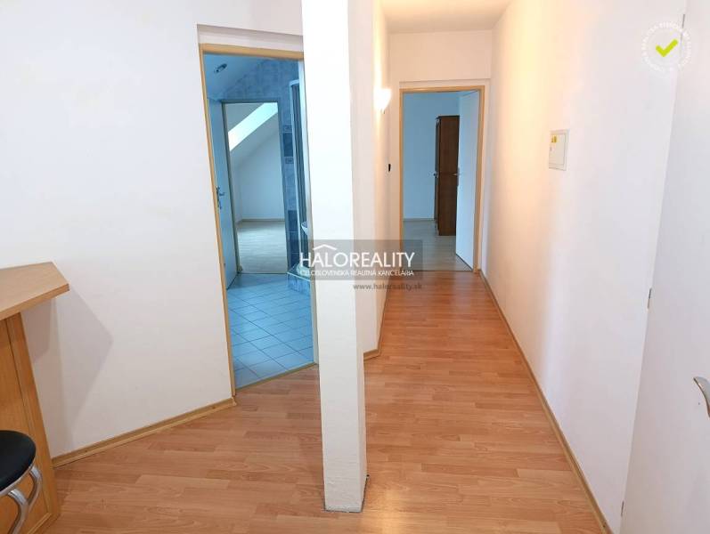 A hallway in a 2-room apartment with a wooden decor floor and an entrance to the bathroom.