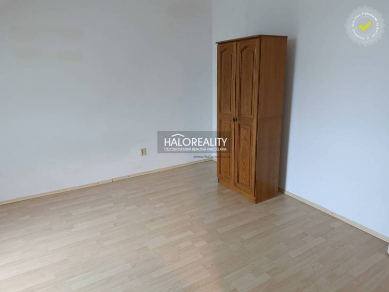 A room in a 2-room apartment with a wooden decor floor and a wardrobe.