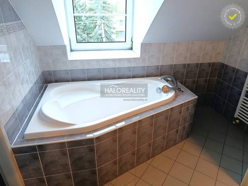 A bathroom in a 2-room apartment with a shower, sink, and light-colored tiles.