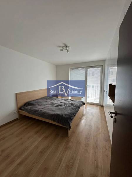 A bedroom with a bed, wooden decor flooring, and a built-in wardrobe in a 2-room apartment.