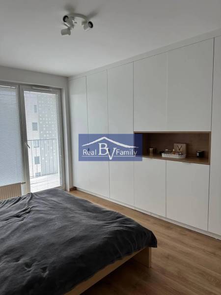 A bedroom with a wood-patterned floor, a large wardrobe, and a bed in a two-room apartment.