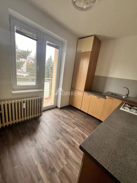 A kitchen in a 3-room apartment with a wooden decor floor and a view of the exterior.