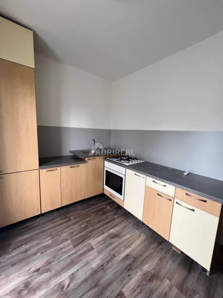 A kitchen in a 3-room apartment with a wooden decor floor and a gas stove.