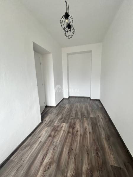 Narrow room with wood-patterned flooring, pendant light, 3-room apartment.