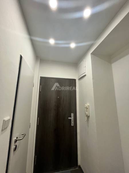 Entrance hallway in a 3-room apartment with white walls and dark doors.