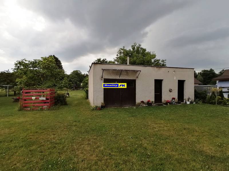 A garden with a building in Turčianske Teplice near a 3-room apartment, surrounded by trees and lawn.