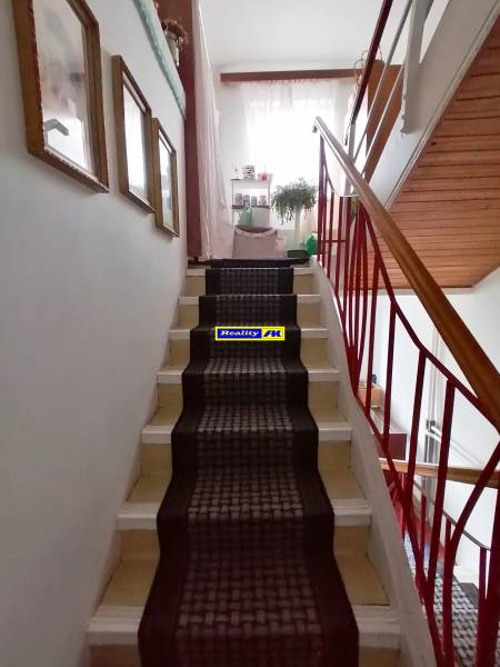 Interior of a 3-room apartment with a staircase, carpet, and railing made of colored metal.