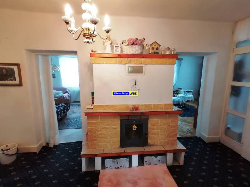 A fireplace in the living room of a three-room apartment with tile decorations and a pendant light.
