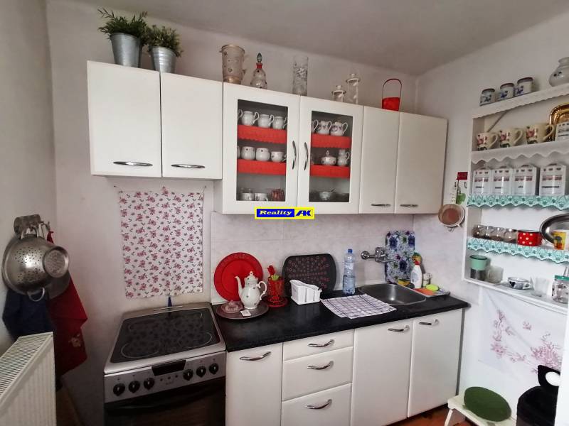 A kitchen in a 3-room apartment with white cabinets and decorative shelves.