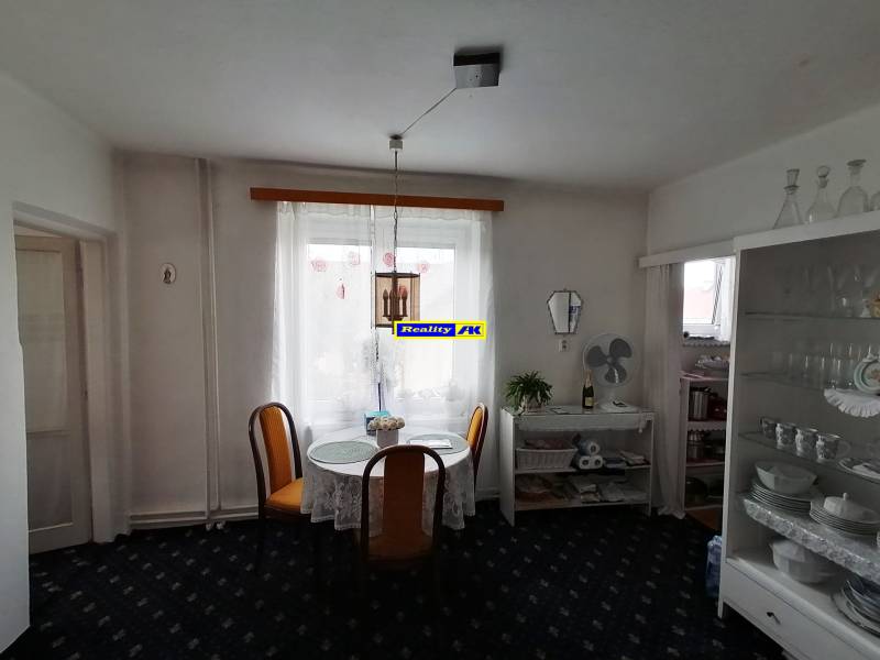 Dining area in a 3-room apartment with floral curtains and a glass cabinet.