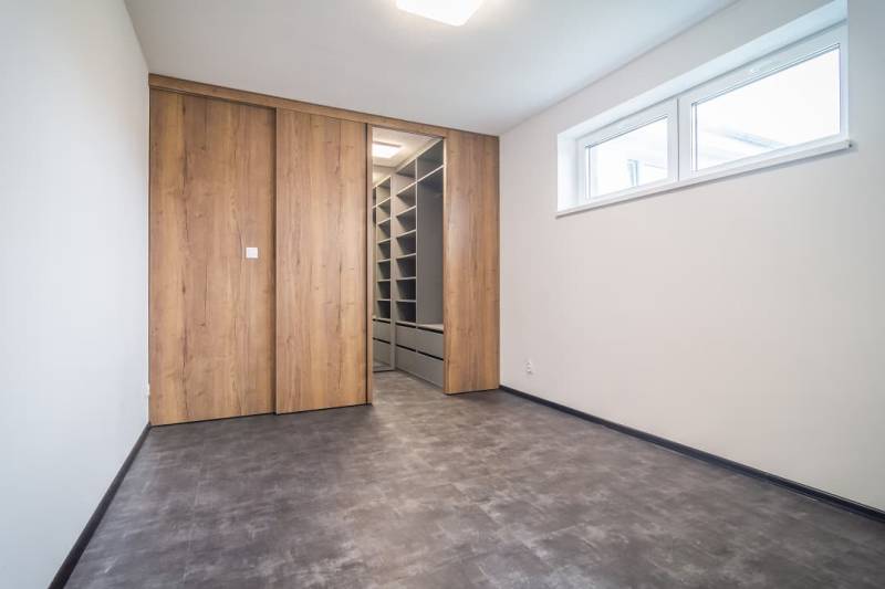 An empty room with a built-in wardrobe and a wooden decor floor in a 2-room apartment.