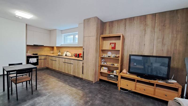 Kitchen corner in a 2-room apartment with a wooden decor floor and dark furniture.