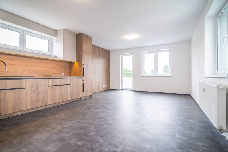 A kitchen in a 2-room apartment with a wooden decor floor and large windows.